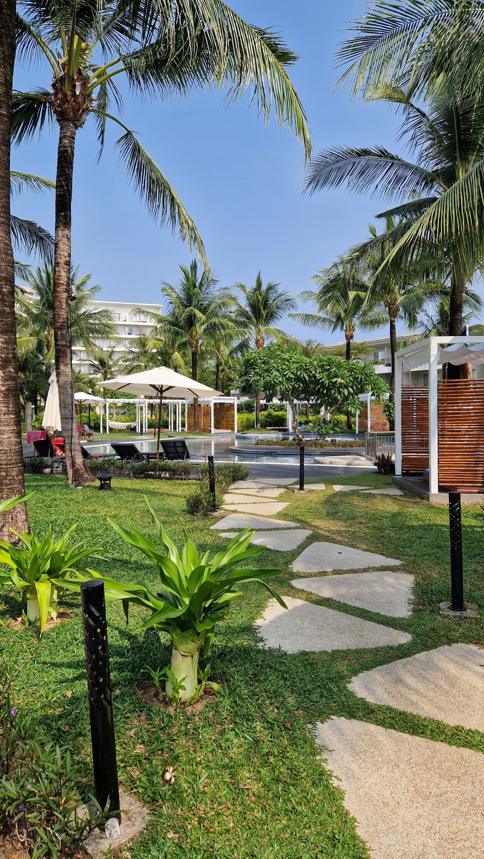 Jardines impecables con pasto verde y palmeras en un resort de Los Cabos